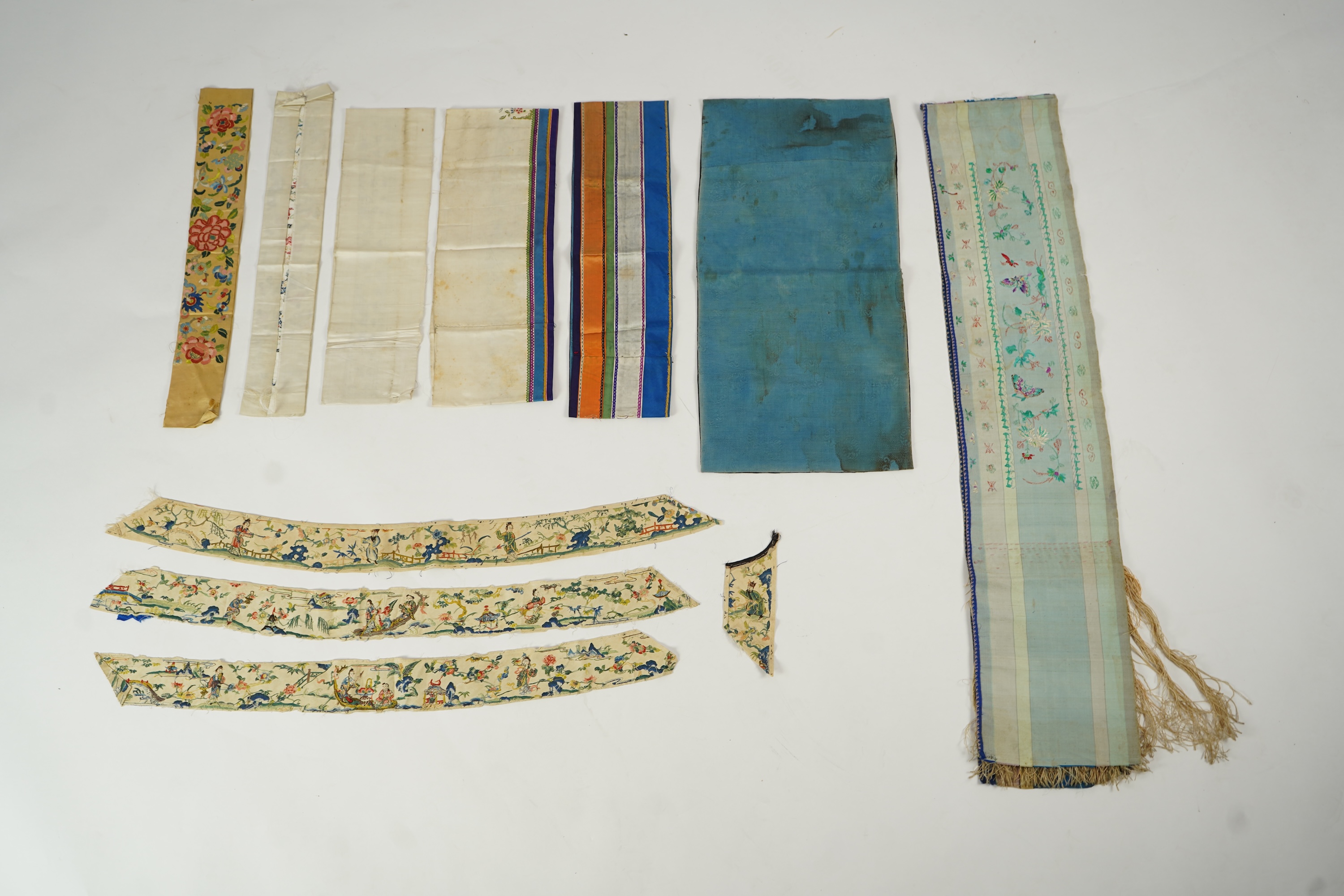 A Chinese embroidered silk panel of uncut robe borders, eleven similar sleeve panels and two other items, late Qing dynasty
